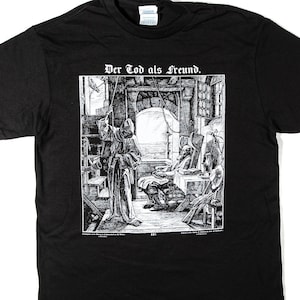 Puede incluir: Camiseta negra con una ilustración en blanco y negro y el texto "Der Tod als Freund." El gráfico representa una escena medieval con figuras en una habitación. La camiseta está hecha de un material suave.