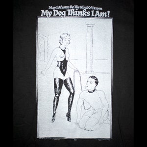 May include: Black and white illustration of a woman in a bodysuit and high heels holding a chain leash. A man is kneeling on the ground with a collar around his neck. The text "May I Always Be The Kind Of Person My Dog Thinks I Am!" is at the top of the image.
