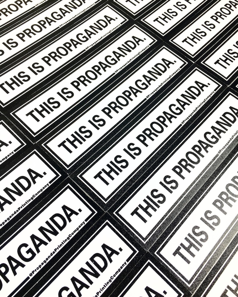 May include: Close-up of multiple black and white stickers with the text "This is Propaganda." printed on them. The stickers are arranged in a staggered pattern, with the text facing the viewer. The stickers are printed by Propaganda Printing Company.