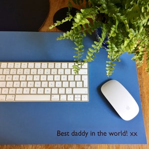 Może przedstawiać: Niebieska mata biurkowa z białą klawiaturą, białą bezprzewodową myszką i tekstem "Best daddy in the world! xx" nadrukowanym na macie.