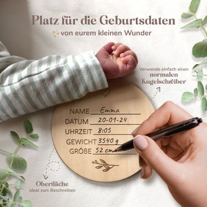 May include: A wooden round plaque with a heart and a small branch design. The plaque has spaces to write the name, date, time, weight, and size of a newborn. The text on the plaque reads "Platz f&uuml;r die Geburtsdaten von eurem kleinen Wunder" and "Verwende einfach einen normalen Kugelschreiber".