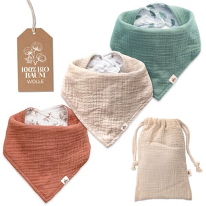 Könnte beinhalten: Set aus drei Bio-Baumwoll-Musselin-Lätzchen in den Farben Terrakotta, Beige und Türkis. Jedes Lätzchen hat ein weißes Baumwoll-Musselin-Futter mit einem Blumendruck. Die Lätzchen werden in einem beigefarbenen Musselin-Kordelzugbeutel mit einem Etikett geliefert, auf dem "100% Bio Baumwolle" steht.