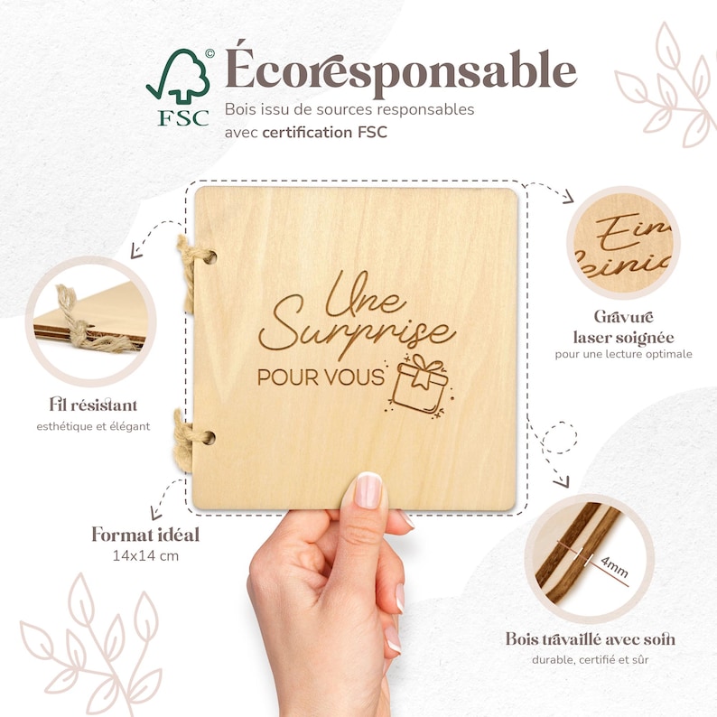 Op de afbeelding: Een houten vierkante geschenkdoos met de tekst "Une Surprise POUR VOUS" en een cadeau-illustratie. De doos is gemaakt van lichtgekleurd hout en wordt door een hand vastgehouden. De doos is 14x14 cm.