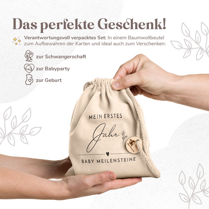 May include: A white canvas bag with a drawstring closure. The bag has black text that reads "Mein erstes Jahr Baby Meilensteine". The bag is being held by a person's hands.