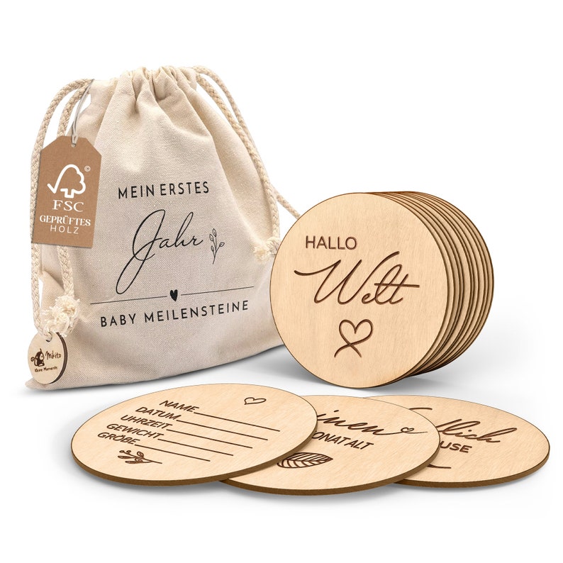 May include: A set of 10 wooden baby milestone discs in a beige drawstring bag. The discs feature phrases like "My First Year", "Hello World", and "First Tooth". The bag has a label that says "My First Year Baby Milestones".