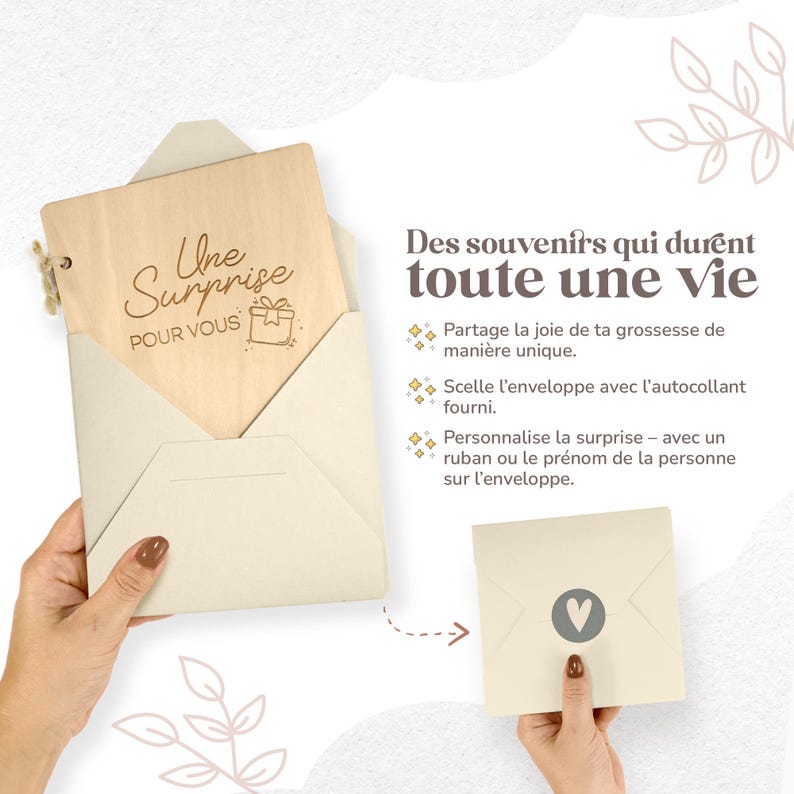 Op de afbeelding: Een houten kaart met de tekst "Une Surprise POUR VOUS" in een cr&egrave;me-kleurige envelop. De kaart wordt in de hand van een persoon gehouden. De afbeelding toont ook een tweede envelop met een hartsymbool.