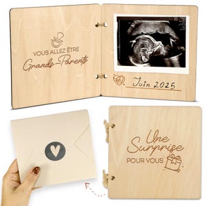 Op de afbeelding: Een houten zwangerschapsaankondigingsalbum met de tekst "VOUS ALLEZ &Ecirc;TRE Grands-Parents" en een echografie. Het album is open, met de echografie en de datum "Juin 2025". Een cr&egrave;me envelop met een hart is ook zichtbaar.