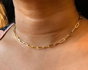 May include: A gold chain necklace with a delicate, linked chain design. The chain is made of small, oval-shaped links.