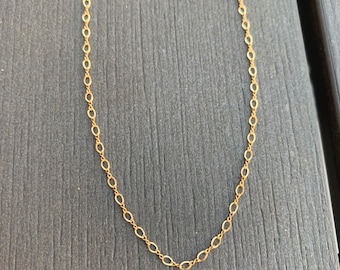 Op de afbeelding: Een gouden ketting met een delicaat ovaal schakeld ontwerp.