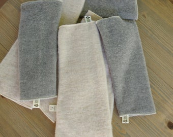 May include: A stack of four gray and cream colored fabric squares with a small tag on each square.