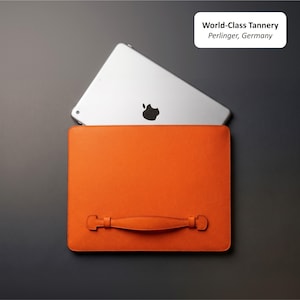 May include: An orange leather tablet case with a handle, holding a silver tablet with the Apple logo. The case is rectangular and has a textured surface. The text "World-Class Tannery Perlinger, Germany" is in the upper right corner.