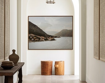 May include: A long, narrow hallway with white walls and arched doorways. Two framed pieces of art hang on the walls, and a wooden console table sits in the centre of the hallway. The console table has a wooden top and legs, and it is decorated with a vase and two bowls. Two wooden stools sit in front of the console table. A rug covers the floor of the hallway. Two hanging light fixtures with glass shades hang from the ceiling.