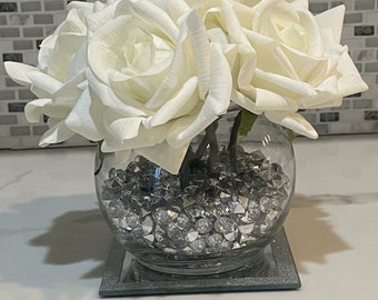 Roses véritables dans un vase fish bowl, centre de table blanc et argent, roses blanches et remplissage de vase imitation losanges argentés, composition florale de roses