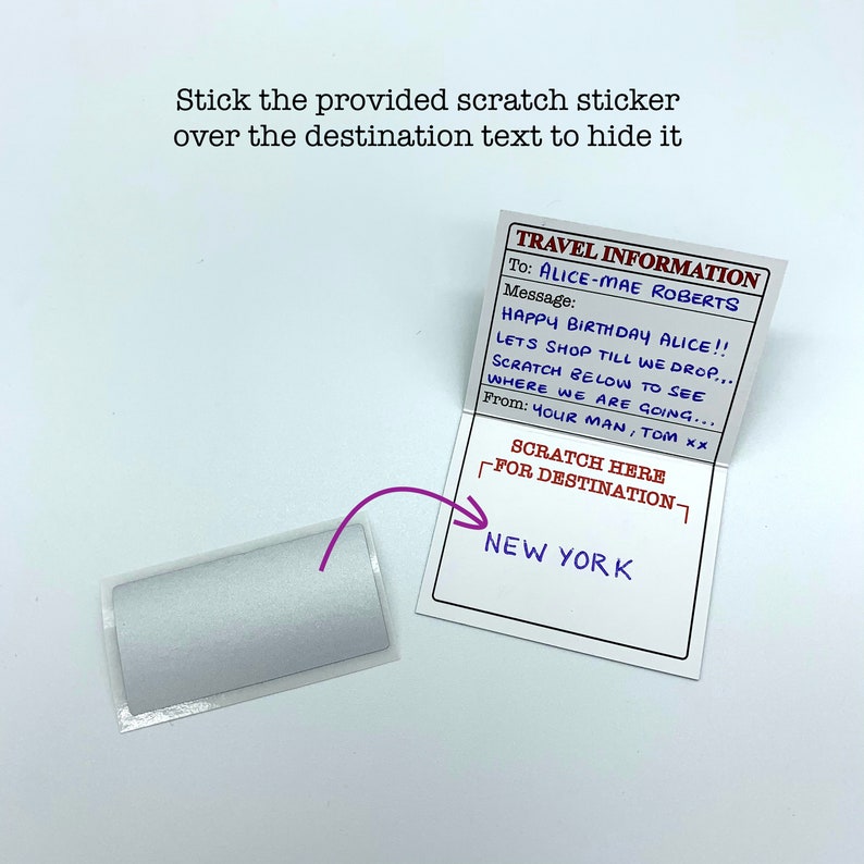 May include: A white card with the text "TRAVEL INFORMATION" and a message that says "HAPPY BIRTHDAY ALICE!! LETS SHOP TILL WE DROP... SCRATCH BELOW TO SEE WHERE WE ARE GOING... From: YOUR MAN, TOM xx". The card also has a scratch-off area that says "SCRATCH HERE FOR DESTINATION" and the text "NEW YORK" underneath.