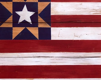 May include: A wooden American flag painted in red, white, and blue with a star in the upper left corner. The flag is made of individual planks of wood, giving it a rustic look.