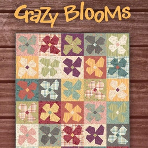 May include: A quilt pattern called "Crazy Blooms" designed by One Sister. The quilt features a patchwork of colorful floral designs in a grid pattern. The quilt is made with a variety of fabrics, including floral prints, stripes, and solids. The quilt is a beautiful example of traditional quilting.