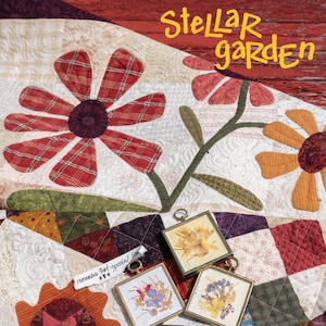 Può includere: Una trapunta con un design a patchwork che presenta fiori, stelle e fiori pressati incorniciati. La trapunta è intitolata "Stellar Garden" ed è realizzata da One Sister Designs.