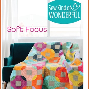 May include: A colorful quilt with a geometric pattern of circles and squares draped over a teal sofa. The quilt features a variety of colors including orange, pink, purple, and yellow. The text "Soft Focus" and "Sew Kind of WONDERFUL" are visible.