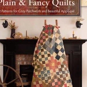May include: A book titled "Plain & Fancy Quilts" with a subtitle "12 Patterns for Cozy Patchwork and Beautiful Appliqué". The book cover features a quilt with a patchwork design in shades of red, brown, blue, and cream. The quilt is draped over a fireplace mantel.