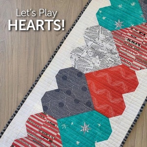 May include: A quilt pattern for a table runner featuring a row of hearts in various colors and patterns. The text "Let's Play HEARTS!" is at the top of the image. The text "ATK-202" is at the bottom of the image. The text "ATKINSON DESIGNS Simple Patterns - Tried and True" is at the bottom of the image.