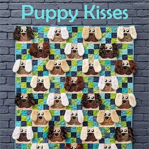 May include: A patchwork quilt featuring repeating dog faces with various fur colors, set against a blue and green checkered background. The words "Puppy Kisses" are at the top. The quilt is bordered in blue. The "Slice of Pi Quilts" logo is at the bottom.