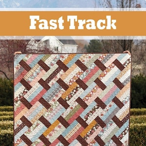 May include: A quilt pattern called "Fast Track" featuring a brown, blue, pink, and yellow chevron pattern. The quilt is made with a variety of floral fabrics. The quilt is displayed on a green lawn with a white house in the background. The image also includes a logo for "a bright corner".