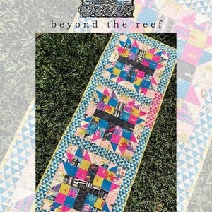 May include: A colorful quilt with a star pattern, featuring pink, blue, and black squares. The quilt is rectangular and has a light blue border with a geometric design. The text "bear crossing" is visible.