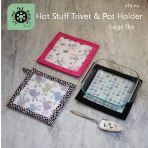 May include: A set of two hot pads and a trivet with a black and white polka dot design, a pink and white floral design, and a blue and white geometric design. The trivet is large and has a black border. The hot pads have a black border with a colorful polka dot trim. The text "Hot Stuff Trivet & Pot Holder" and "Large Size" is visible in the image.