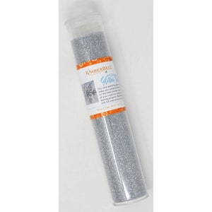 May include: A clear plastic tube filled with silver glitter. The label reads "Kamberbell Applique Glitter Silver Size: 19.5 x 7.5"