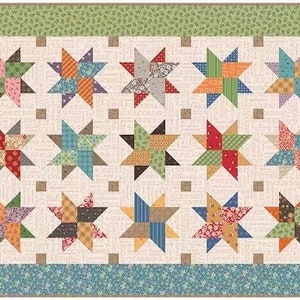 Könnte beinhalten: Eine Steppdecke mit Patchwork-Muster, die ein sich wiederholendes Muster aus Sternen zeigt, die aus verschiedenen farbigen Stoffquadraten bestehen. Die Steppdecke ist mit einem Rand aus gemustertem Stoff eingefasst.