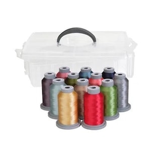 Puede incluir: Una caja de almacenamiento de plástico transparente con un asa negra, que contiene carretes de hilo de bordar de colores. Los colores del hilo incluyen dorado, rojo, verde y azul. Los carretes están dispuestos en semicírculo.