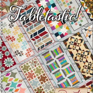 May include: A book titled "Tabletastic!" featuring colourful quilt designs for table runners. The book cover features a variety of quilt patterns, including stars, geometric shapes, and floral designs. The book is by Doug Leko, Antler Quilt Designs.