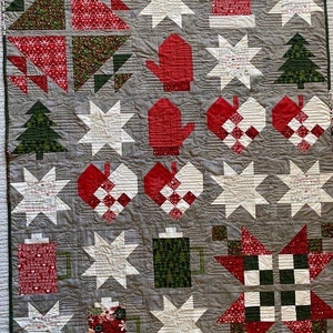 May include: A gray and white quilt with a Christmas theme. The quilt features a variety of blocks, including stars, trees, mittens, and hearts. The blocks are made in a variety of fabrics, including red, green, and white. The quilt is quilted with a simple stitch pattern.
