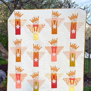 May include: A white quilt featuring repeating angel figures with crowns, wings, and star accents. The angels are in various colors, including red, orange, and yellow. The quilt has the text "How Does Your Garden Grow #261" and the Cotton Street Commons logo.