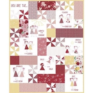 May include: A white quilt with a patchwork design featuring various colorful patterns and illustrations of girls. The quilt has a yellow border and the text "YOU ARE THE..." in the top left corner. The quilt is made up of squares with different designs, including flowers, sprinkles, cookies, and a rainbow.