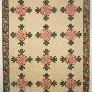 May include: A cream-colored quilt with a repeating pattern of pink and green flowers. The quilt has a green and pink floral border.
