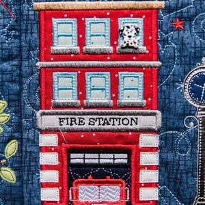 May include: A red brick fire station building with white windows and a fire truck inside. The building has a sign that reads "FIRE STATION".