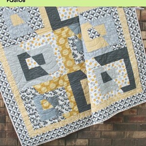 May include: A quilt pattern called "Tabitha" by The Fat Quarter Gypsy. The quilt is made with a variety of fabrics in shades of gray, yellow, and white. The quilt is hanging on a brick wall. The text "FQG108" is in the upper left corner of the image. The text "Tabitha" is in the lower center of the image. The text "A fun and easy fat quarter friendly weekend quilt" is below the text "Tabitha".