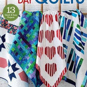 May include: A book titled "One Day Quilts" with the subtitle "13 Quick & Easy Projects" featuring three different quilt designs: a blue and green patchwork quilt, a white quilt with red hearts, and a blue and white striped quilt.