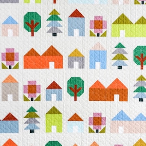 May include: A colorful quilt with a repeating pattern of houses, trees, and flowers. The quilt is made with a variety of fabrics in shades of red, orange, yellow, green, blue, and pink.