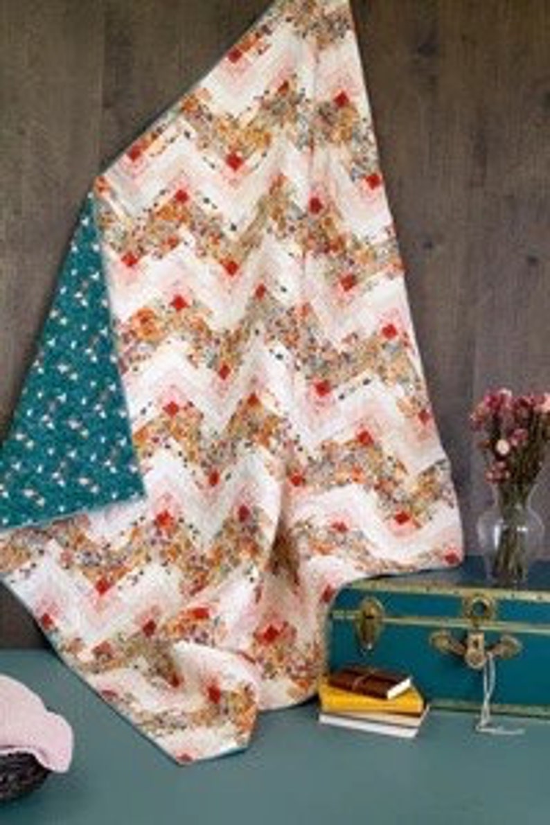 May include: A white ceramic mug with a black handle and the text "But First, Coffee" in a bold, black font. The mug is set against a blurred background, suggesting a cozy setting.