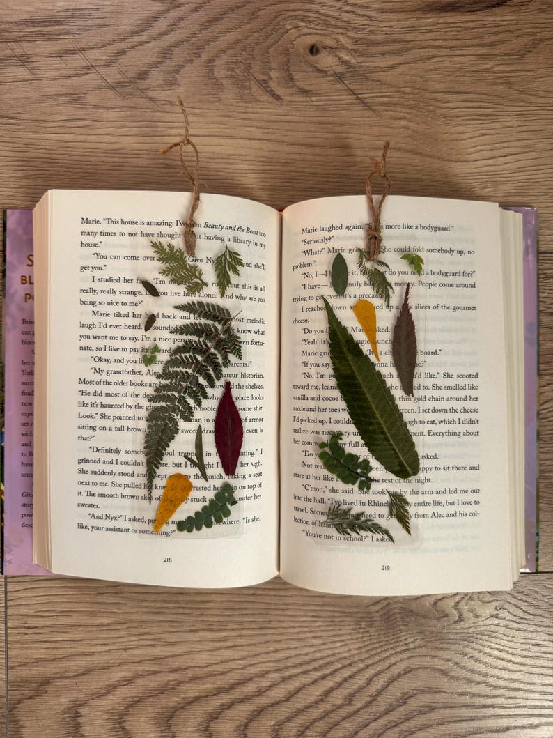 May include: Two open books with pressed flowers and leaves as bookmarks. The text on the left page reads "Ten Beauty and the Beast" and the text on the right page reads "If you say so."