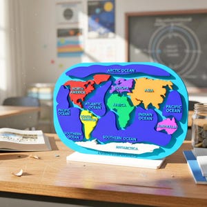 May include: A colorful, three-dimensional world map model with continents in red, yellow, green, orange, and pink, and oceans in blue. The map is on a white base, set on a wooden desk in a classroom setting. The map is labeled with the names of the continents and oceans.