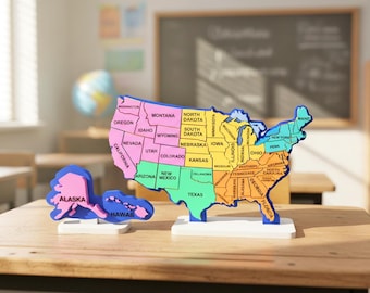 Puede incluir: Rompecabezas de madera colorido de los Estados Unidos, con cada estado etiquetado y pintado de un color diferente. El estado de Alaska está separado. El rompecabezas está sobre un escritorio de madera en un aula.