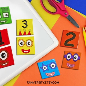 Pode incluir: Um conjunto de ímãs quadrados coloridos com números e rostos. Os ímãs estão em uma superfície branca com uma superfície amarela e laranja atrás deles. Os ímãs são perfeitos para aprender números e cores.