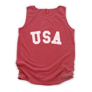 Pu&ograve; includere: Canotta rossa senza maniche con la scritta "USA" stampata in bianco sul davanti.