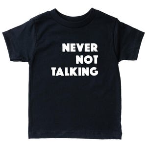 May include: A black short-sleeved t-shirt featuring the white text NEVER NOT TALKING printed in a bold, sans-serif font across the chest. The garment has a crew neckline and a standard fit, with the text arranged in three stacked lines.
