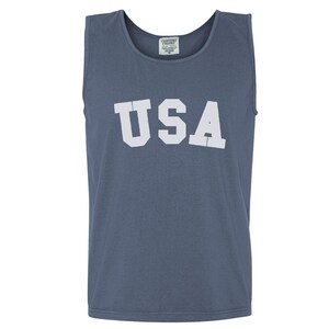 Pu&ograve; includere: Una canotta blu con la scritta "USA" stampata in bianco sul davanti.