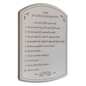 May include: A rectangular plaque with a curved top, featuring the text "THE 10 COMMANDMENTS." The text is in a serif font, with decorative floral accents. The commandments are listed below the title, in a simple, easy-to-read format.