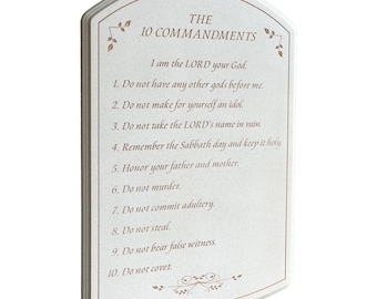May include: A rectangular, off-white plaque with a decorative border and the text "THE 10 COMMANDMENTS" in a serif font. The text of the commandments is printed below in a smaller font. Floral accents are in the corners.